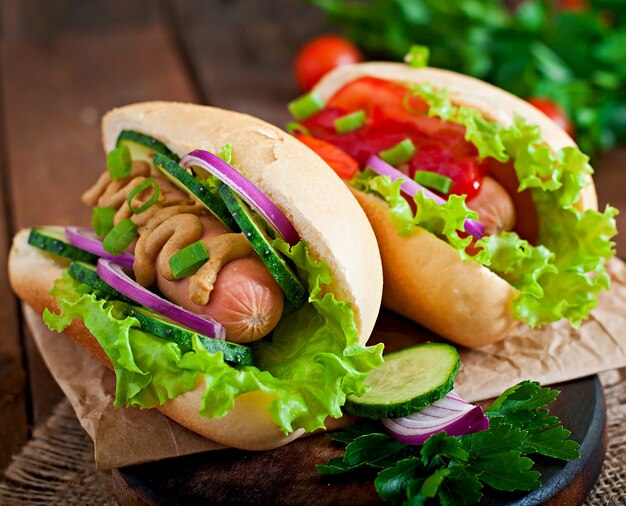 Hotdog met ketchup, mosterd, sla en groenten op houten tafel