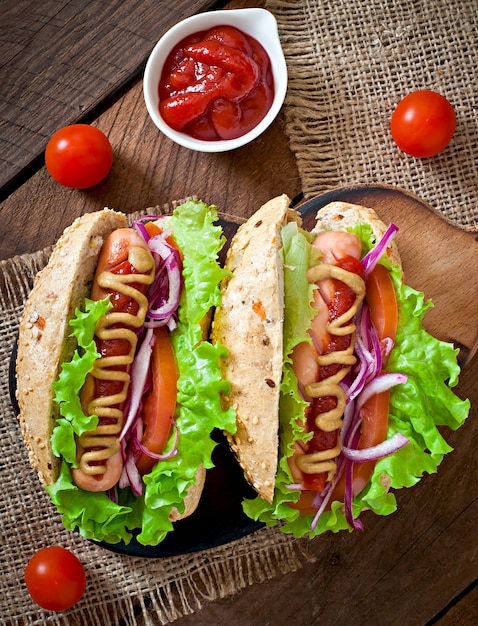 Hotdog met ketchupmosterd en sla op houten lijst.
