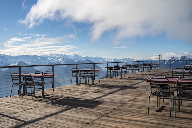 Hotelbalkon met tafels en stoelen met uitzicht op de omliggende Alpen en meren op een bewolkte dag