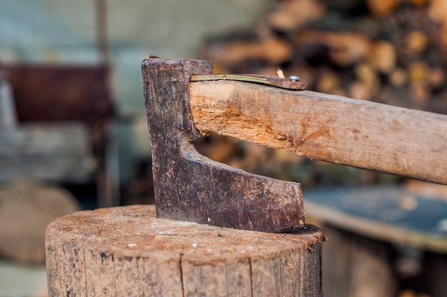 Hout hakken met bijl. Axe vast in een logboek van hout. Oude, versleten, gekraste, scherpe bijl die staat op een houten, gebarsten boomstomp op een achtergrond van gehakt hout.