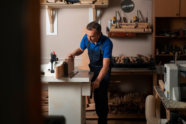 Gratis foto houtbewerker in zijn winkel die werkt met gereedschappen en apparatuur