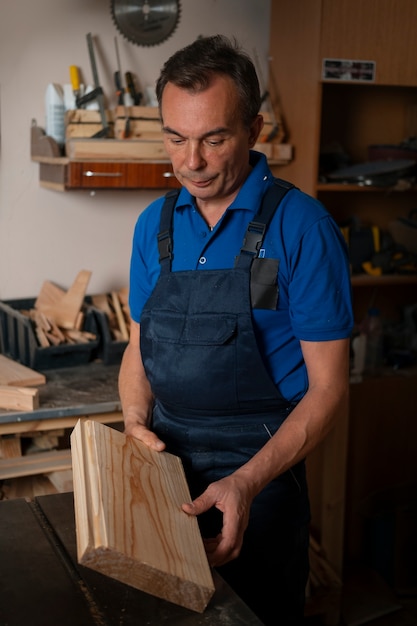 Gratis foto houtbewerker in zijn winkel die werkt met gereedschappen en apparatuur