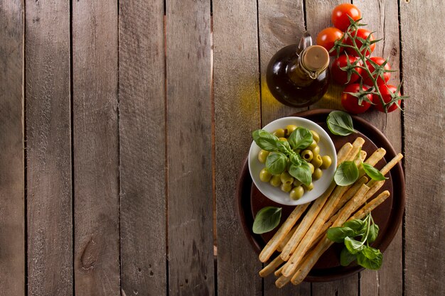 Houten achtergrond met olijfolie, tomaten en olijven