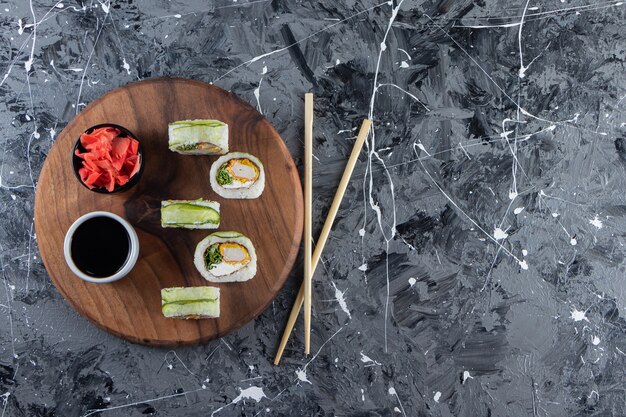 Houten bord met groene drakensushi rolt op marmeren achtergrond.