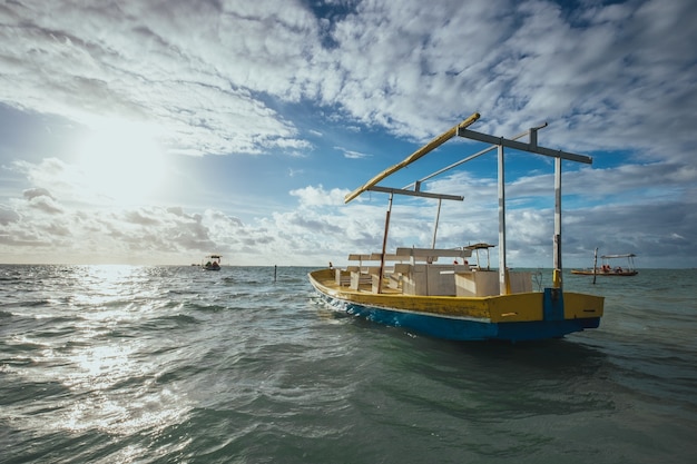 Houten handgemaakte boot op de zee onder het zonlicht en een bewolkte hemel