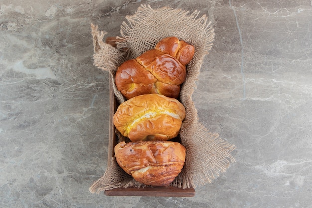 Gratis foto houten kist met verschillende smakelijke gebakjes op marmeren backgroudn