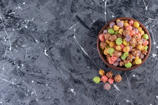 Houten kom met heerlijke kleurrijke popcorns op marmeren achtergrond.
