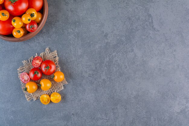 Houten kom met kleurrijke biologische tomaten op stenen oppervlak