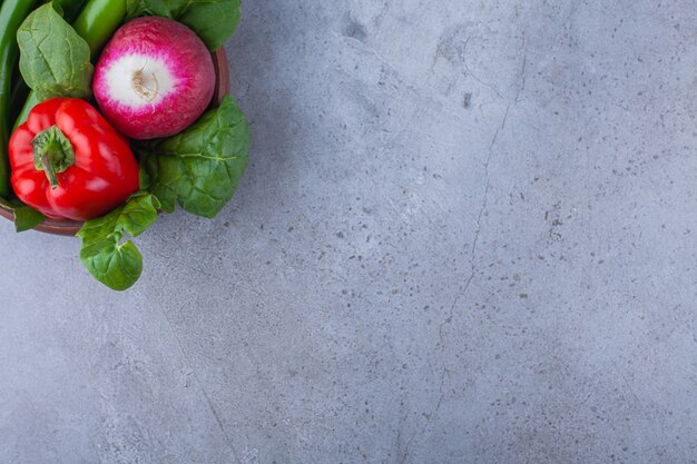 Houten kom paprika met radijs op blauwe tafel.