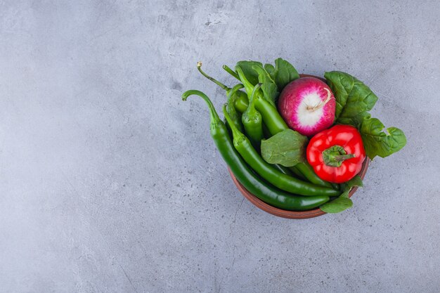 Houten kom van chili en paprika met radijs op blauwe achtergrond.