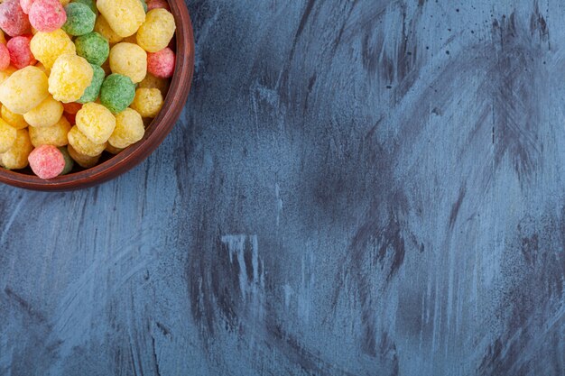 Houten kom vol met kleurrijke graanballen op blauw.