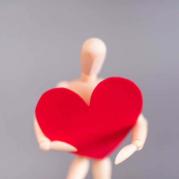 Gratis foto houten ledenpop die groot rood hart houdt