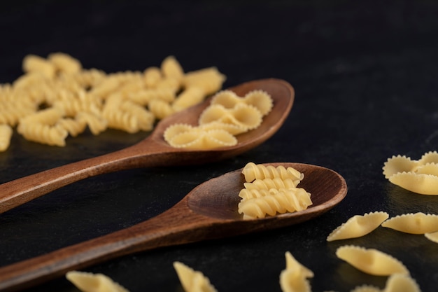 Houten lepels vol rauwe girandole en farfalle tonde pasta.