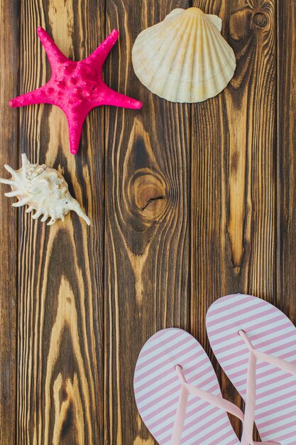 Houten oppervlak met zeeschelpen en flip-flops