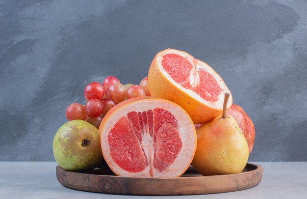 Houten plank vol seizoensfruit en half gesneden grapefruit.