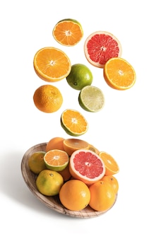 Houten schotel met geassorteerde sinaasappelen en mandarijnen vliegen, geïsoleerd van de witte achtergrond