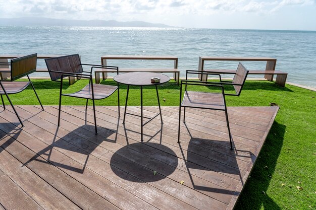 Houten tafel en stoelen in leeg strandcafé naast zeewater. detailopname. eiland koh phangan, thailand