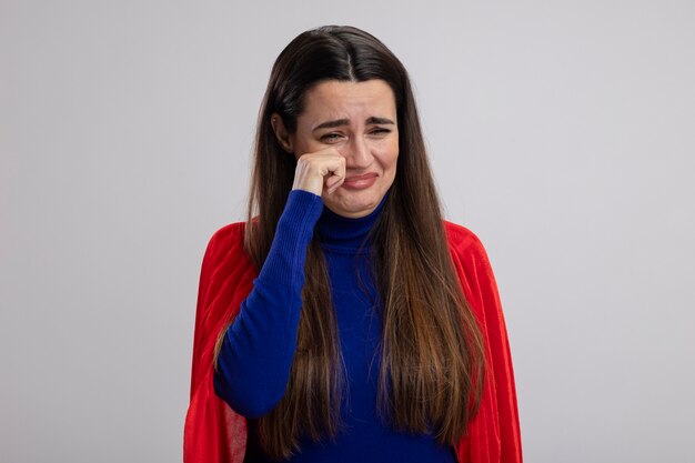 Huilende jonge superheld meisje afvegende ogen met hand geïsoleerd op wit