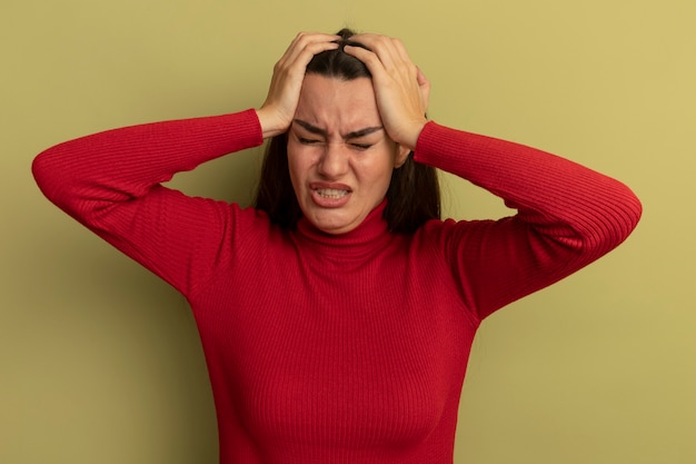 Gratis foto huilende vrij blanke vrouw handen op het hoofd op olijfgroen