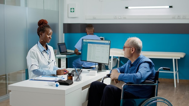 Huisarts doet controlebezoek met patiënt in rolstoel, consulteert oude man met chronische handicap. Dokter doet onderzoek met rolstoelgebruiker die lijdt aan een beperking.