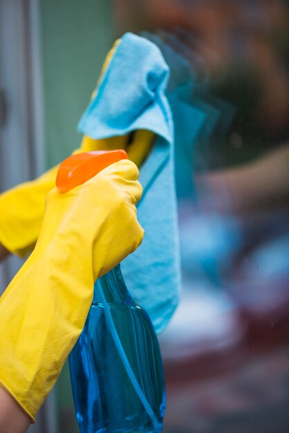 Huishoudster bespuitend detergent met nevelfles op glasvenster