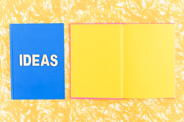 Ideeënboek dichtbij het open gele paginaboek op gele achtergrond