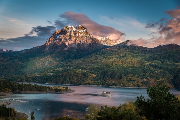 Idyllische opname van een enorme berg bedekt met vegetatie met een watermassa aan de voet