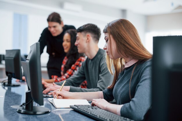 Iedereen doet zijn werk. Groep jongeren in vrijetijdskleding in het moderne kantoor