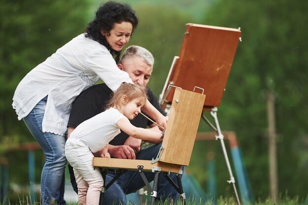 Iedereen is bezig. Grootmoeder en grootvader hebben buiten plezier met kleindochter. Schilderij conceptie