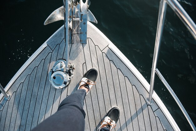 Iemands voeten op de boot die overdag op zee vaart