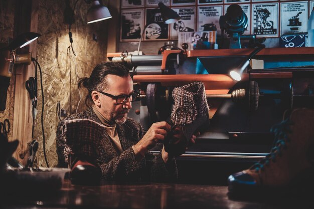 Ijverige volwassen schoenontwerper werkt op workshop aan zijn nieuwe schoenencollectie.