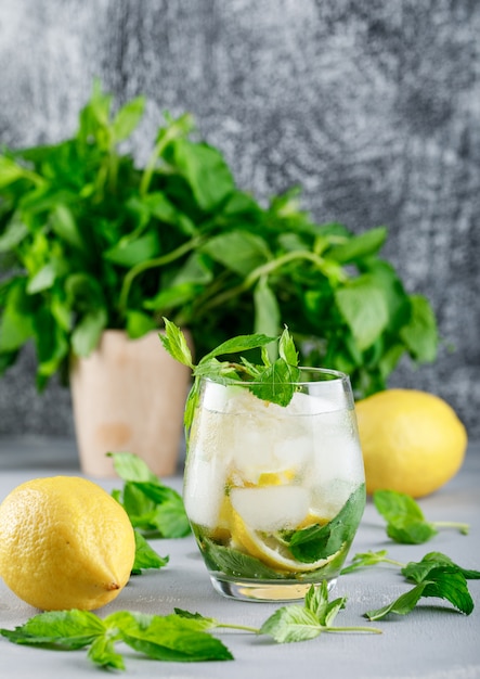 IJzig detox water met citroenen en munt in een glas op grijs en grunge oppervlak
