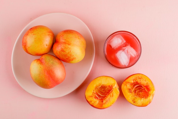 IJzig sap in een glas met platte nectarines lag op een roze oppervlak