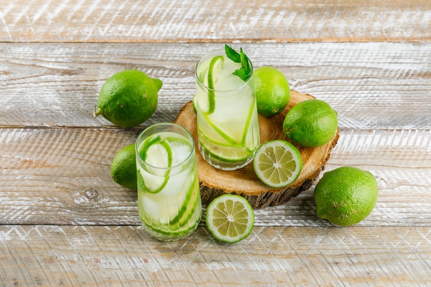 IJzige limonade in glazen met citroen, basilicum plat lag op houten en snijplank