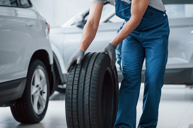 Ik ben onderweg. Monteur met een band bij de reparatiegarage. Vervanging van winter- en zomerbanden