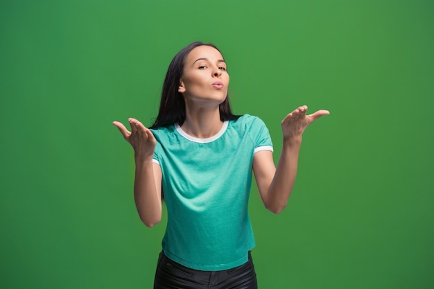 Ik kus je. Portret van aantrekkelijke vrouw met kus op lippen. Groene studio. Mooi vrouwelijk portret. Jonge gelukkige emotionele grappige vrouw