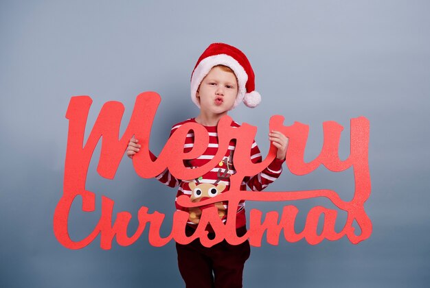 Ik wens jou een prettig kerstfeest. Jongen met vrolijk kerstfeest belettering