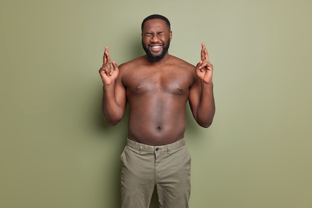 Ik wil winnen. Positieve donkere huid Afro-Amerikaanse man kruist vingers doet wens heeft hoop op betere poses met naakte torso