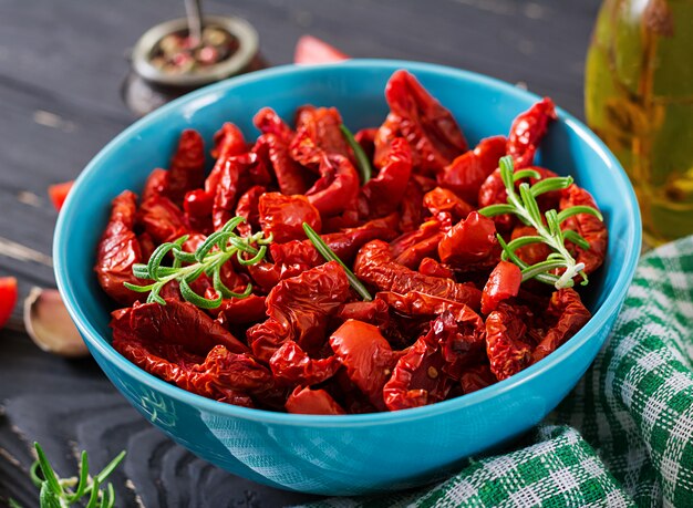 In de zon gedroogde tomaten met kruiden en knoflook in kom op houten lijst. Italiaans eten.