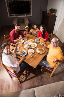 Indiase familie eten aan de eettafel thuis of in een restaurant samen eten