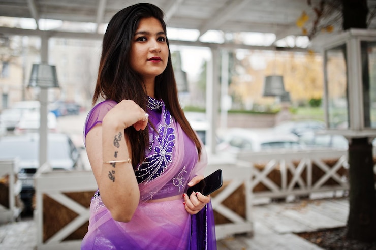 Gratis Foto indiase hindoe meisje op traditionele violet saree geposeerd op straat tegen houten terras