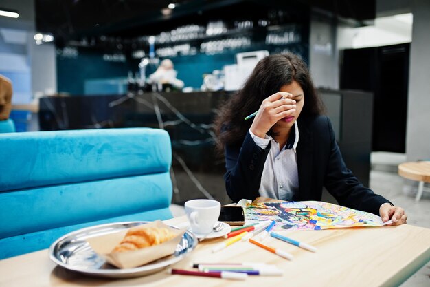 Indiase kunstenaarsvrouw draagt een formele verffoto terwijl ze in café zit