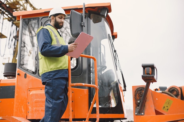 Indiase man aan het werk. Mannetje in een geel vest. Man bij de tractor.