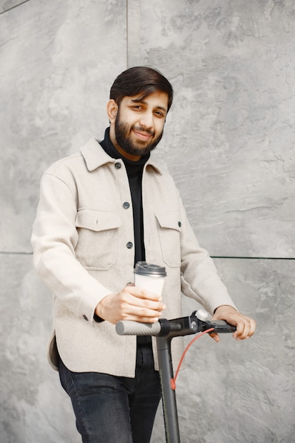 Indiase man rijdt op een elektrische scooter. man met koffie.