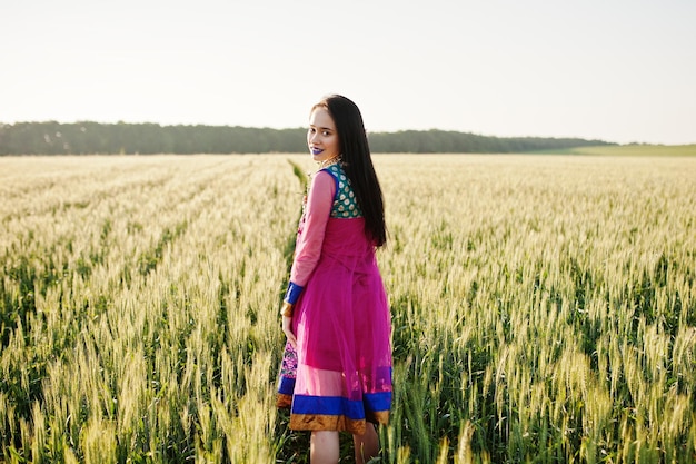 Indisch meisje in saree met paarse lippen make-up geposeerd op veld in zonsondergang Modieus Indiaas model