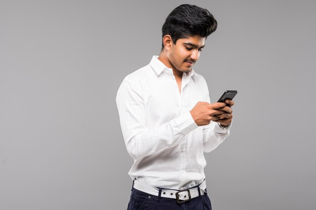 Indische bedrijfsmens die smartphone met witte muur gebruiken