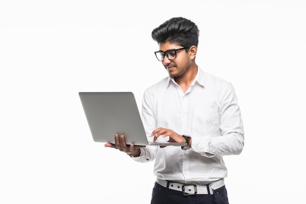 Indische jonge man met laptop geïsoleerd op een witte muur
