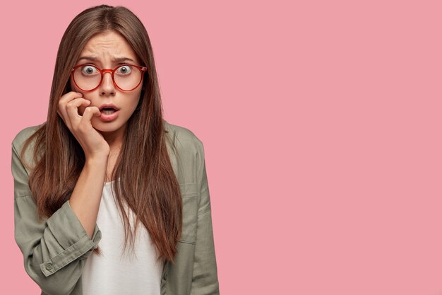 Indoor shot van verbaasde student poseren tegen de roze muur