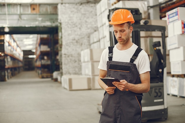 Industriële werknemer binnenshuis in fabriek. Jonge technicus met oranje bouwvakker.