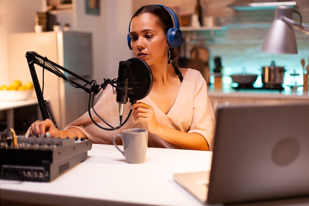 Influencer die een koptelefoon draagt en nieuwe podcastseries opneemt voor haar publiek. On-air online productie internetuitzending show host streaming live inhoud, opname van digitale sociale media-communicatie